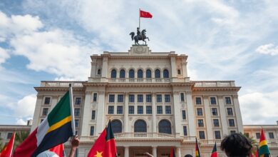Bandeiras acenando diante de um imponente edifício governamental histórico sob céu nublado europeu.